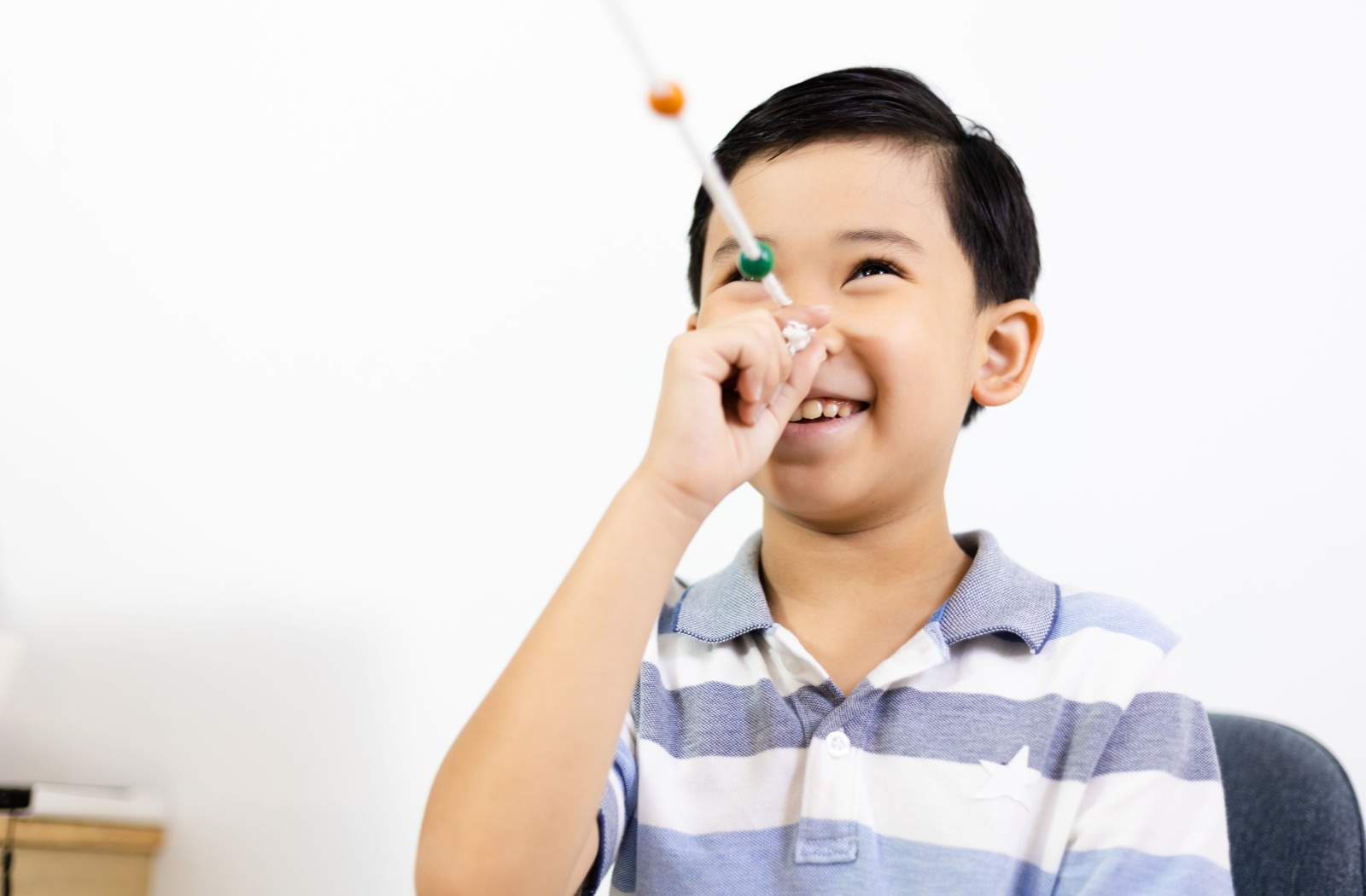 Smiling boy performing a Brock string exercise during vision therapy to improve eye coordination and focus.