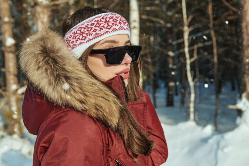 Woman outside during winter wearing winter jacket and sunglasses.